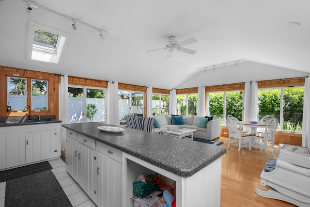5 Highland Ln, Harwich Port, MA 02646 - kitchen featuring rail lighting, vaulted ceiling, dark countertops, a skylight, and a center island