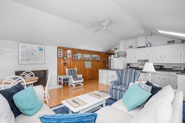 5 Highland Ln, Harwich Port, MA 02646 - living area with light wood-type flooring, vaulted ceiling, a ceiling fan, wood walls, and a skylight