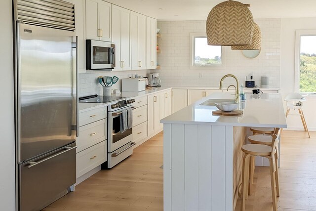 kitchen featuring sink, white cabinetry, a center island with sink, and appliances with stainless steel finishes