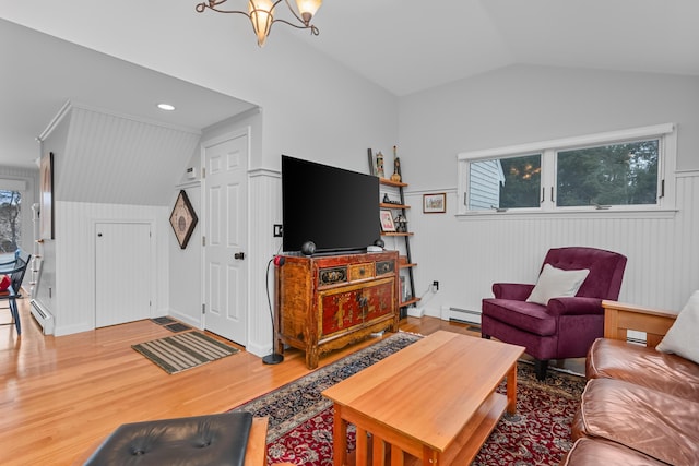 living room with vaulted ceiling, wood-type flooring, a baseboard heating unit, and a notable chandelier