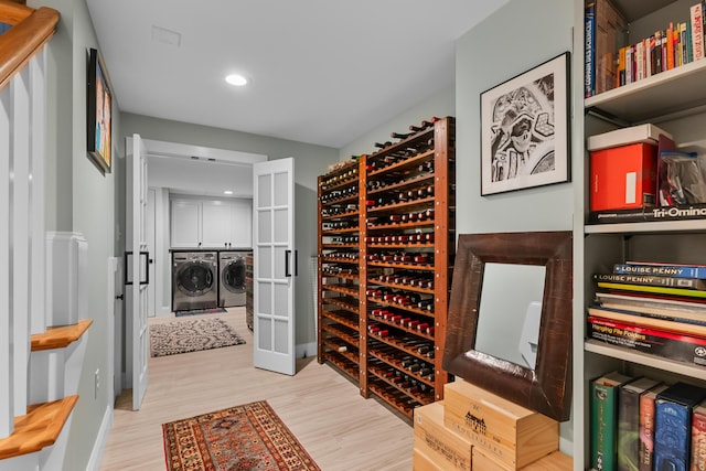 wine room with separate washer and dryer and light wood-type flooring