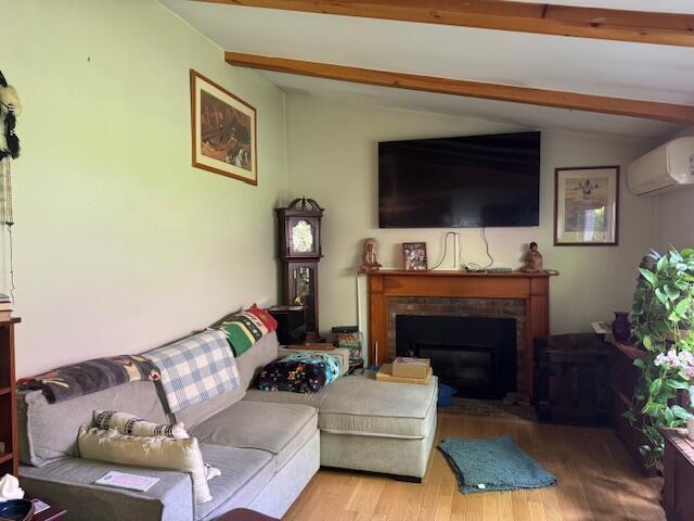 155 Mitchells Way, Barnstable, MA 02601 - living area with wood finished floors, a brick fireplace, and a wall mounted air conditioner
