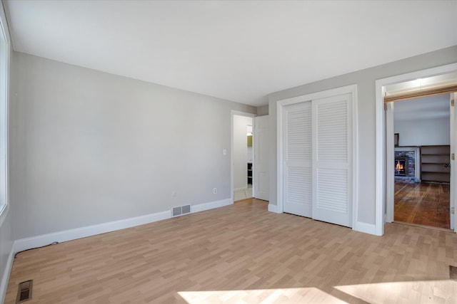4 Inkberry Cir, Sandwich, MA 02563 - unfurnished bedroom with light wood-type flooring, a warm lit fireplace, baseboards, and visible vents
