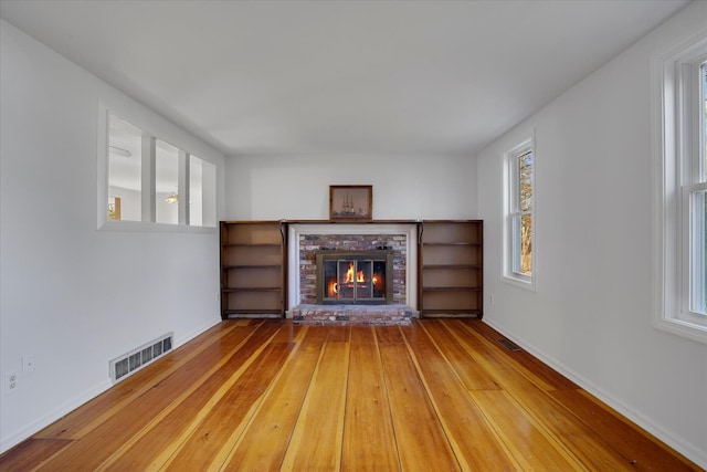 4 Inkberry Cir, Sandwich, MA 02563 - unfurnished living room with hardwood / wood-style floors, a brick fireplace, visible vents, and a wealth of natural light