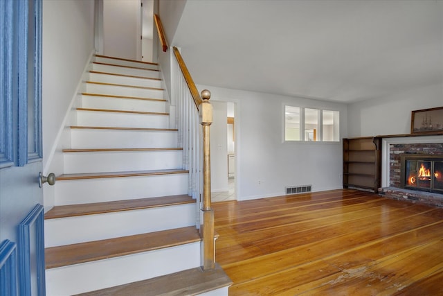 4 Inkberry Cir, Sandwich, MA 02563 - staircase featuring a brick fireplace, wood-type flooring, and visible vents