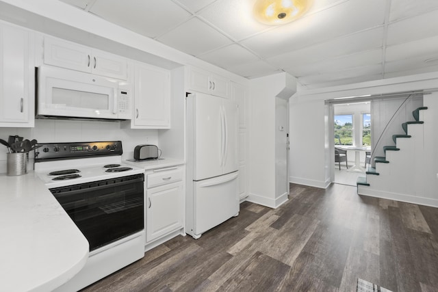 kitchen featuring white appliances, white cabinets, dark hardwood / wood-style flooring, and a drop ceiling