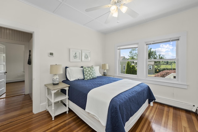 bedroom with ceiling fan, a baseboard heating unit, and dark wood-type flooring