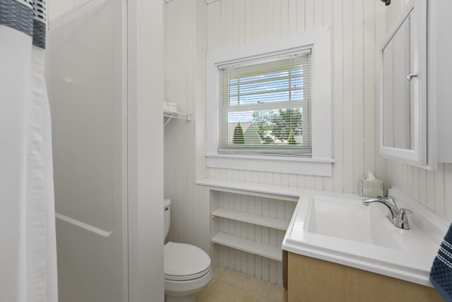 bathroom featuring wooden walls, toilet, tile patterned flooring, and vanity