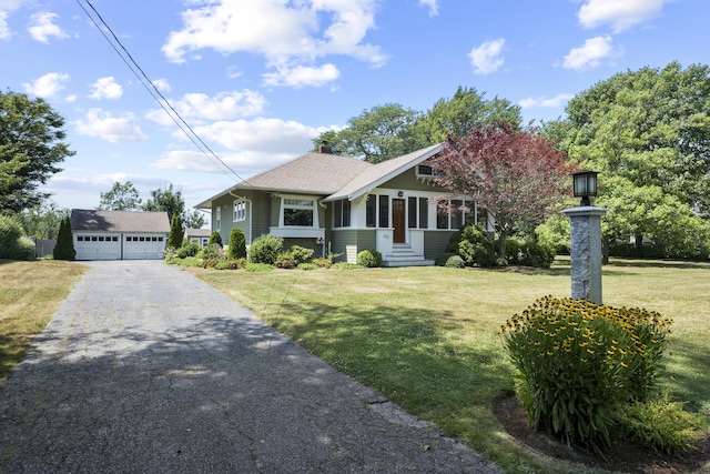 view of front facade featuring a garage, an outbuilding, and a front lawn