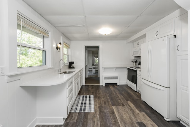 kitchen with radiator heating unit, white appliances, white cabinetry, a drop ceiling, and sink