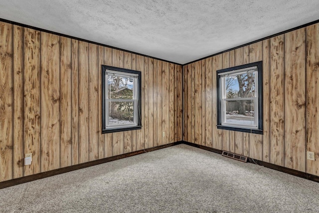 unfurnished room featuring crown molding, carpet flooring, wooden walls, and a textured ceiling