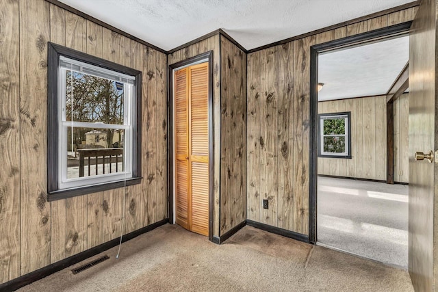 corridor with crown molding, plenty of natural light, light carpet, and a textured ceiling