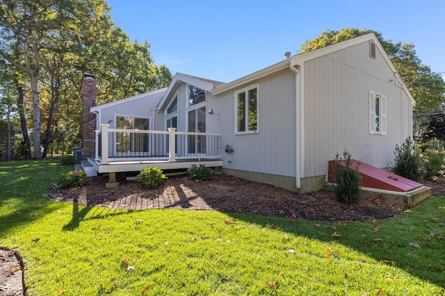 rear view of property featuring a lawn and a wooden deck