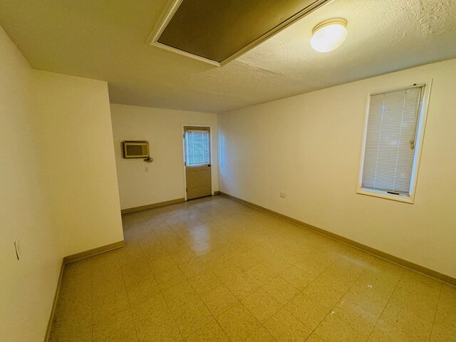 empty room featuring a wall mounted air conditioner and a textured ceiling