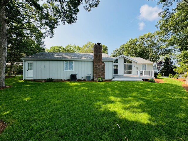 rear view of property featuring a wooden deck, a lawn, and central AC