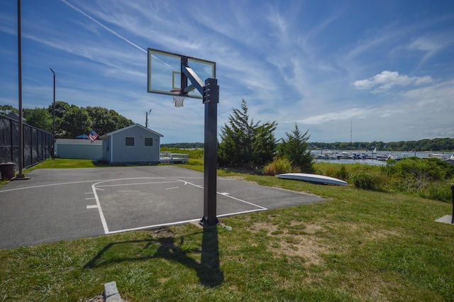 view of basketball court with a water view and a yard