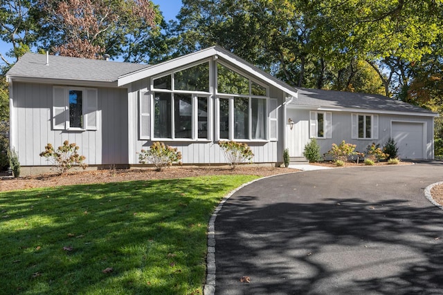 ranch-style home with a garage and a front lawn