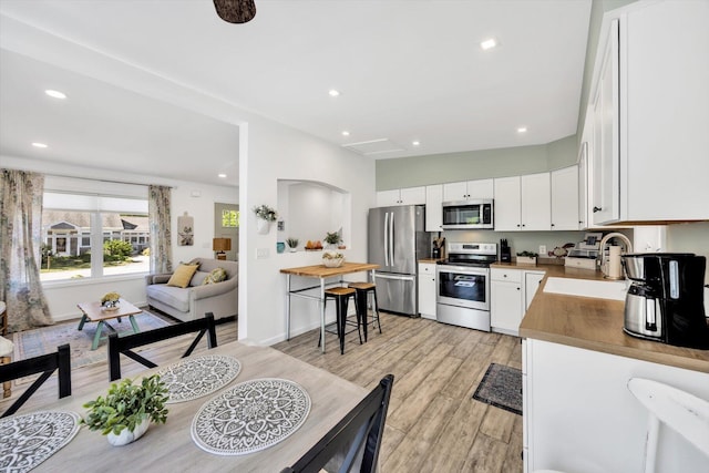 39 Nehoiden Rd, Mashpee, MA 02649 - kitchen with stainless steel appliances, a sink, light wood-style floors, white cabinetry, and recessed lighting