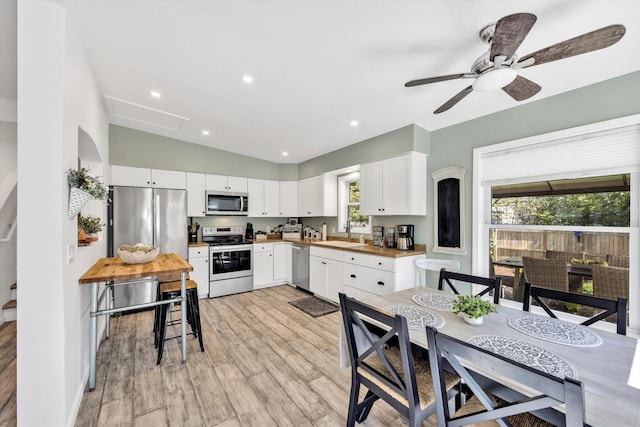 39 Nehoiden Rd, Mashpee, MA 02649 - kitchen featuring appliances with stainless steel finishes, a sink, vaulted ceiling, light wood-type flooring, and white cabinetry