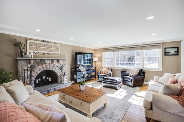 living room featuring baseboards, a fireplace, recessed lighting, light wood-style floors, and crown molding