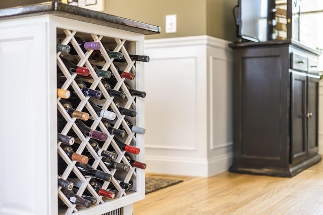 wine area with a decorative wall, wainscoting, and wood finished floors