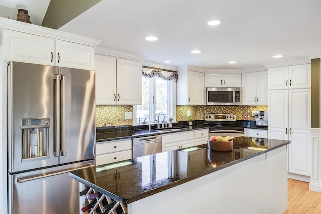 kitchen featuring a sink, white cabinetry, stainless steel appliances, light wood-style floors, and decorative backsplash