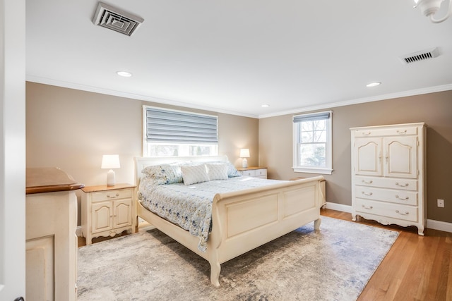 bedroom featuring visible vents, light wood-style flooring, and ornamental molding