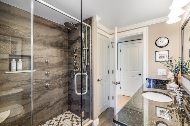 bathroom with a sink, double vanity, a stall shower, and ornamental molding