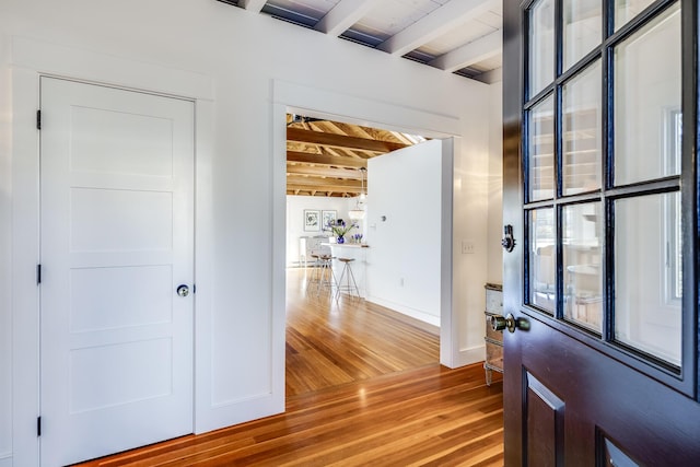 entryway with wood ceiling, wood finished floors, beam ceiling, and baseboards