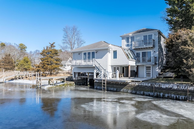 back of property with a balcony, stairs, and concrete driveway