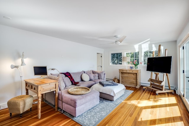 living area featuring a baseboard radiator, wood finished floors, and a ceiling fan