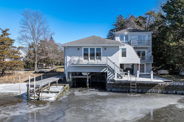 back of property featuring driveway, a shingled roof, a balcony, boat lift, and a deck