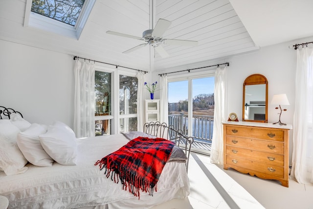 bedroom featuring access to outside, a water view, a skylight, and a ceiling fan