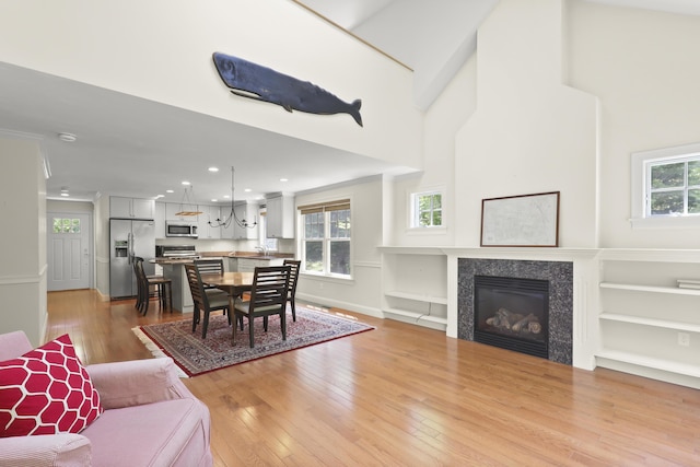 21 Pine St Unit 1Au, North Falmouth, MA 02556 - dining space with light wood-style floors, a tiled fireplace, recessed lighting, built in shelves, and a towering ceiling