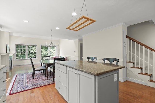 21 Pine St Unit 1Au, North Falmouth, MA 02556 - kitchen with a center island, a chandelier, light wood-style flooring, white cabinetry, and crown molding