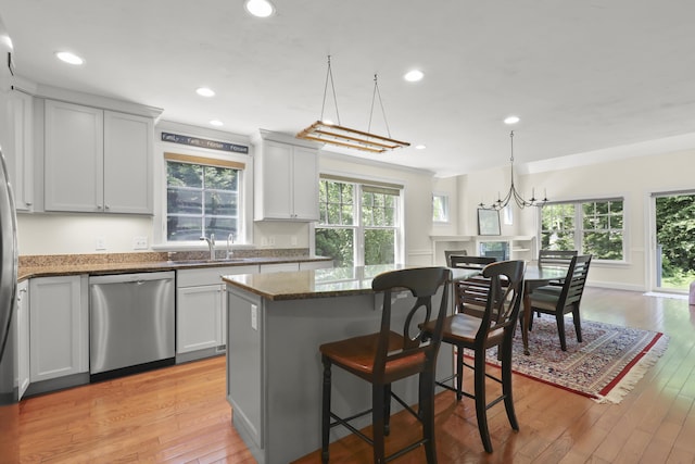 21 Pine St Unit 1Au, North Falmouth, MA 02556 - kitchen featuring stainless steel dishwasher, dark stone countertops, a kitchen island, light wood-type flooring, and a kitchen bar