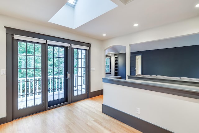 doorway to outside with light hardwood / wood-style flooring and a skylight