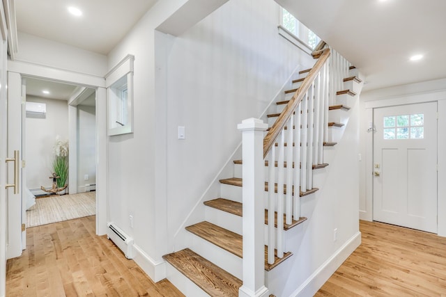 staircase featuring a wall mounted AC, hardwood / wood-style floors, and baseboard heating