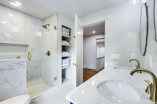 bathroom with a shower with shower door, built in shelves, toilet, and vanity