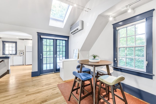 dining area with light hardwood / wood-style floors, a healthy amount of sunlight, lofted ceiling, and a wall mounted air conditioner