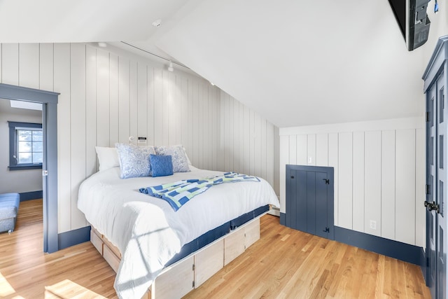 bedroom with light hardwood / wood-style floors and lofted ceiling