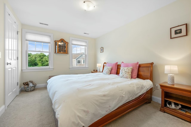 bedroom with baseboards, visible vents, and light colored carpet