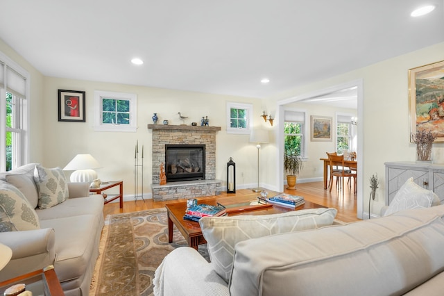 living area featuring light wood-style floors, recessed lighting, baseboards, and a stone fireplace