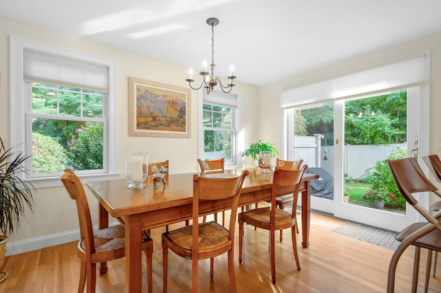 dining area featuring light wood finished floors, baseboards, and a chandelier