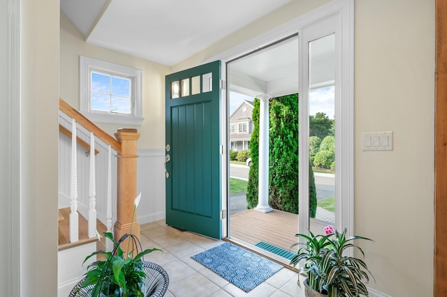 entrance foyer featuring light tile patterned floors, stairway, and wainscoting