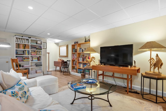 living area featuring light wood finished floors, baseboards, and a drop ceiling