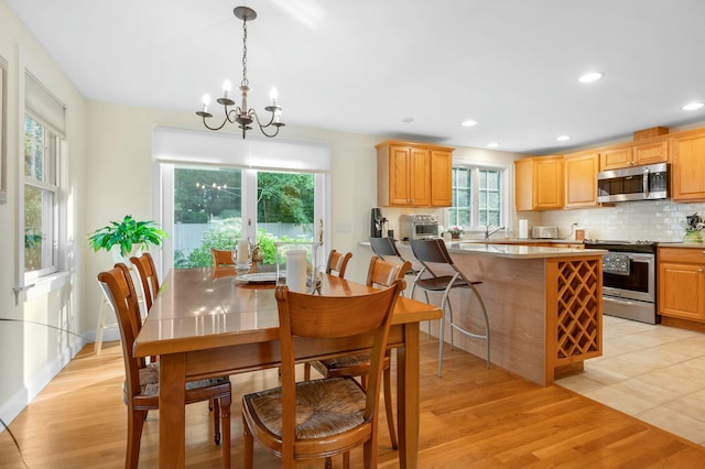 dining area with baseboards, light wood finished floors, an inviting chandelier, and recessed lighting