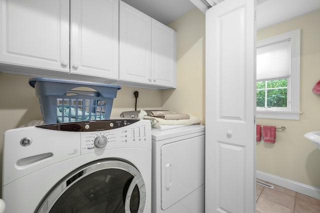 laundry area with washing machine and clothes dryer, light tile patterned floors, cabinet space, visible vents, and baseboards