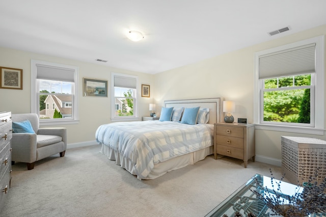 bedroom featuring multiple windows, visible vents, and light colored carpet