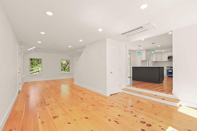 2 Little Cove Ln, Orleans, MA 02653 - unfurnished living room featuring light wood-style flooring, recessed lighting, baseboards, a sink, and lofted ceiling